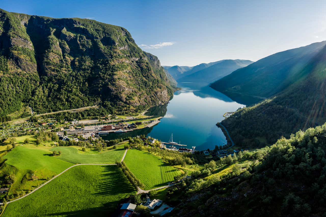 Aerial view of a fjord surrounded by bright green mountains and fields