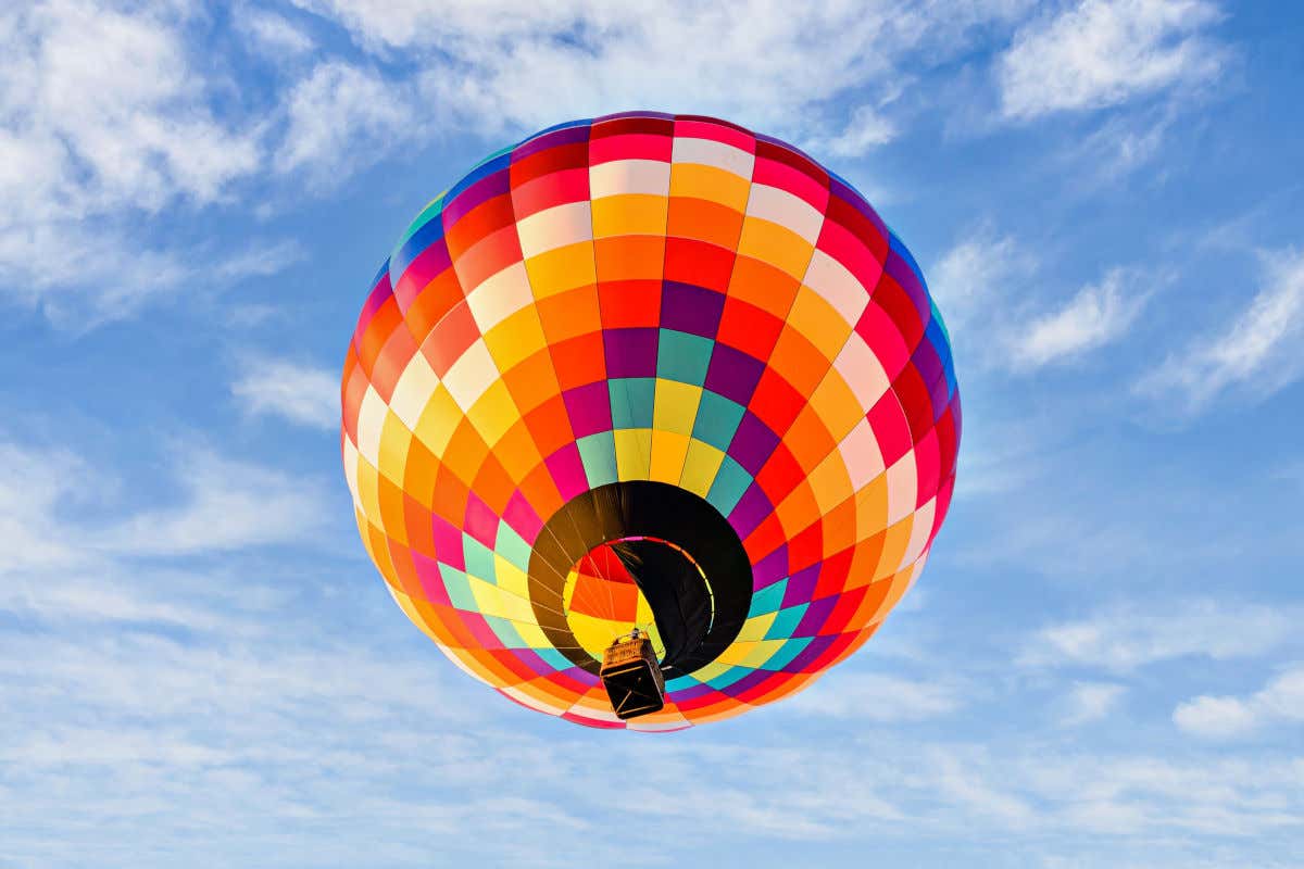 Una mongolfiera dai colori vivaci che vola in una giornata limpida con cielo azzurro e poche nuvole