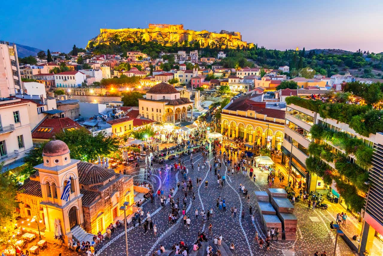 The area of Monastiraki at night, as seen from above, with large parts of the city lit up in an orange light.