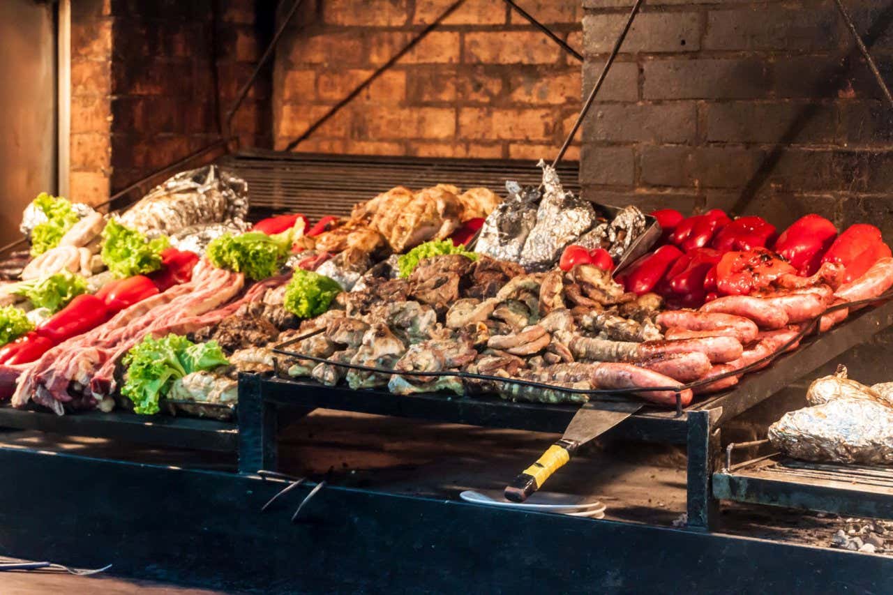 A grill of lots of types of meat and sausages, red pepper and lettuce