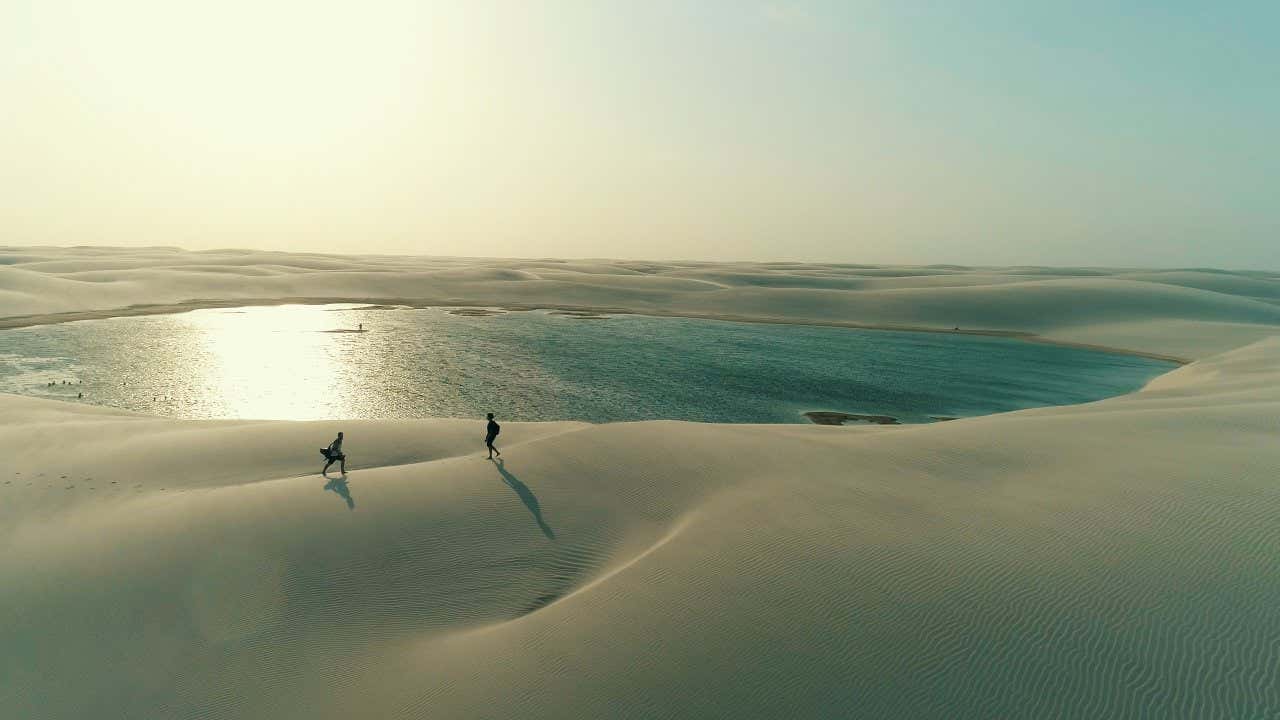 Personnes sur le sable au bord d'un lagon turquoise au coucher du soleil