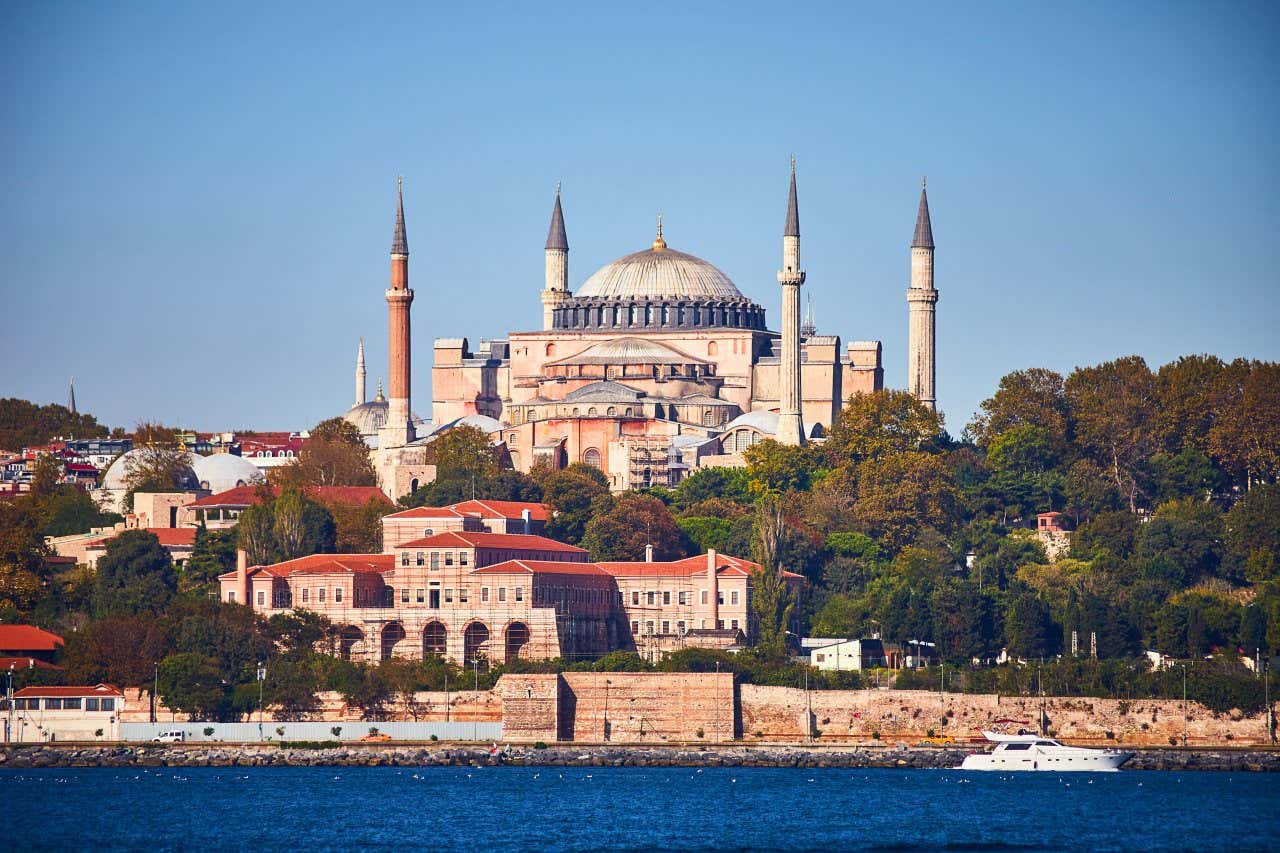 Santa Sofia, em Istambul, vista da água, com um céu claro ao fundo.