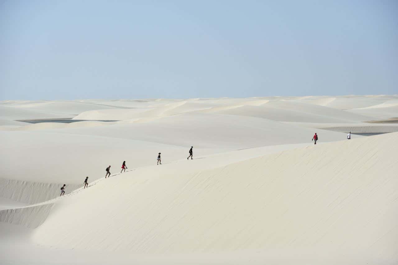 Personnes marchant le long des dunes de sable blanc aux Lençóis Maranhenses 