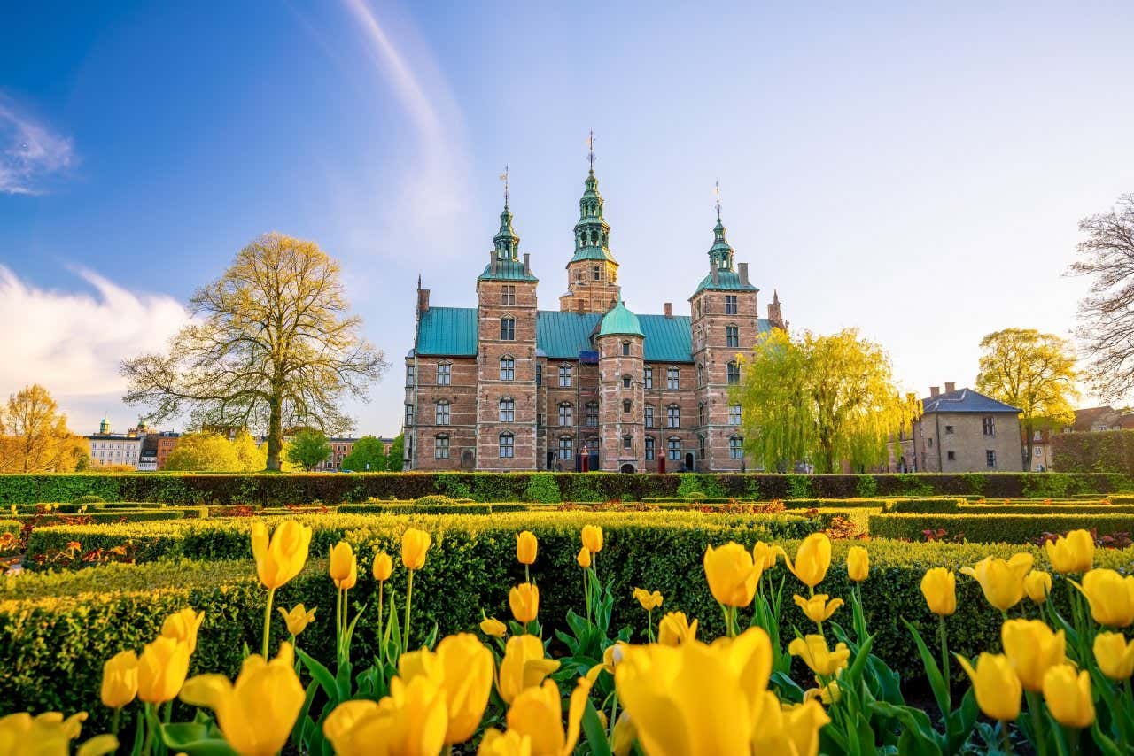 Rosenborg castle behind neat garden with yellow tulips in Copenhagen.