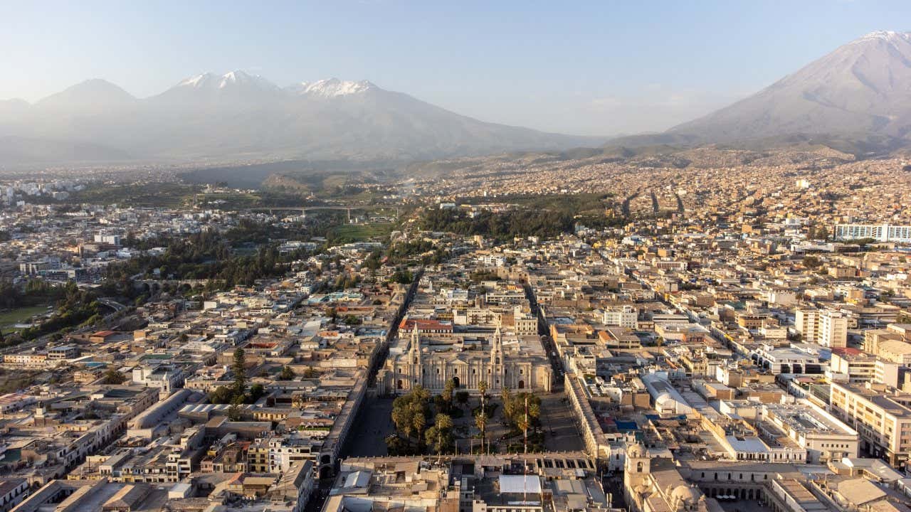 A cidade de Arequipa vista de cima com vulcões ao fundo e palácios brancos