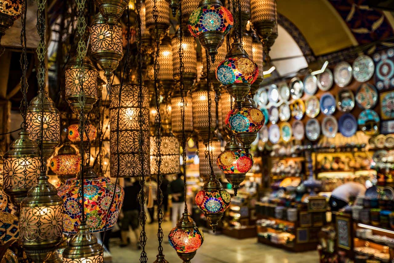 Em primeiro plano, lâmpadas no Grande Bazar de Istambul, com um comerciante ao fundo.