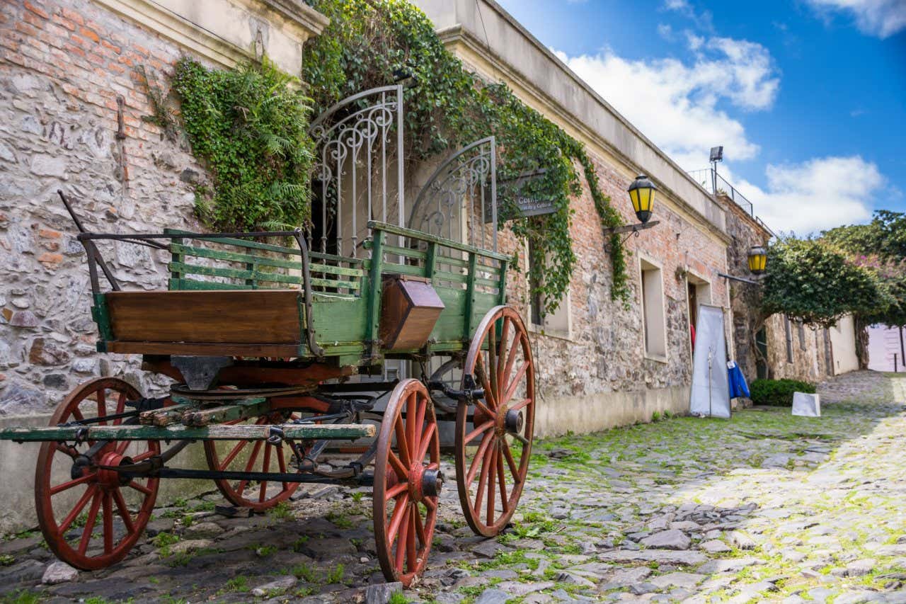 Uma antiga carruagem sobre uma rua de pedras ao lado de um edifício colonial