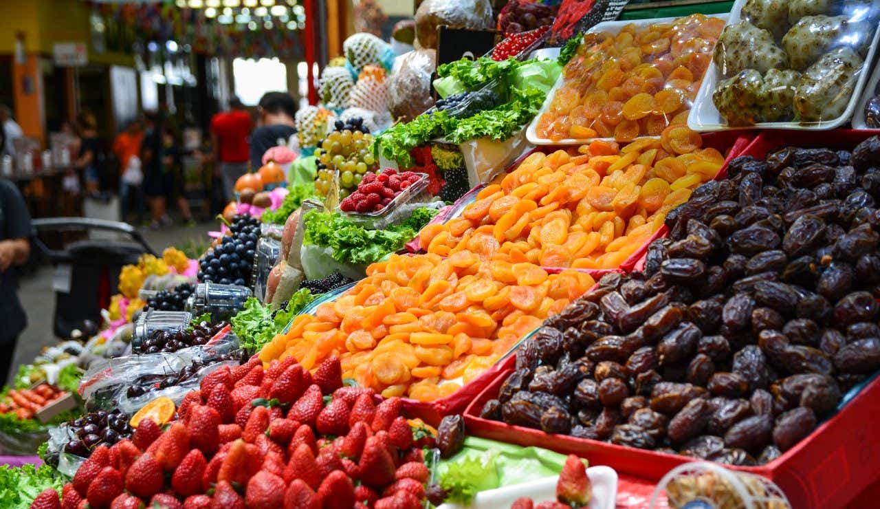 Un'invitante e colorata bancarella di frutta e verdura nel Mercado Municipal, in cui si vedono datteri, fragole, frutta secca e lattuga.