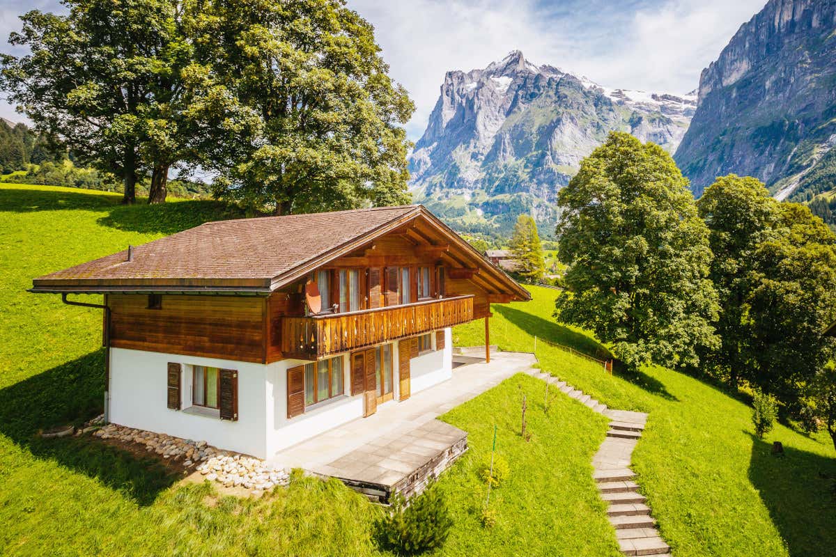 Casa con techo de madera situada a los pies de una montaña alpìna