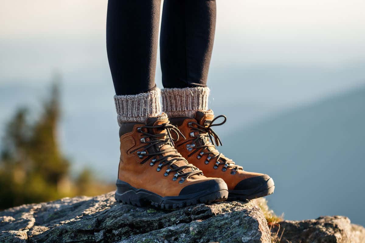 Dos piernas femeninas con unos leggins y unas botas de senderismo pisando sobre unas rocas