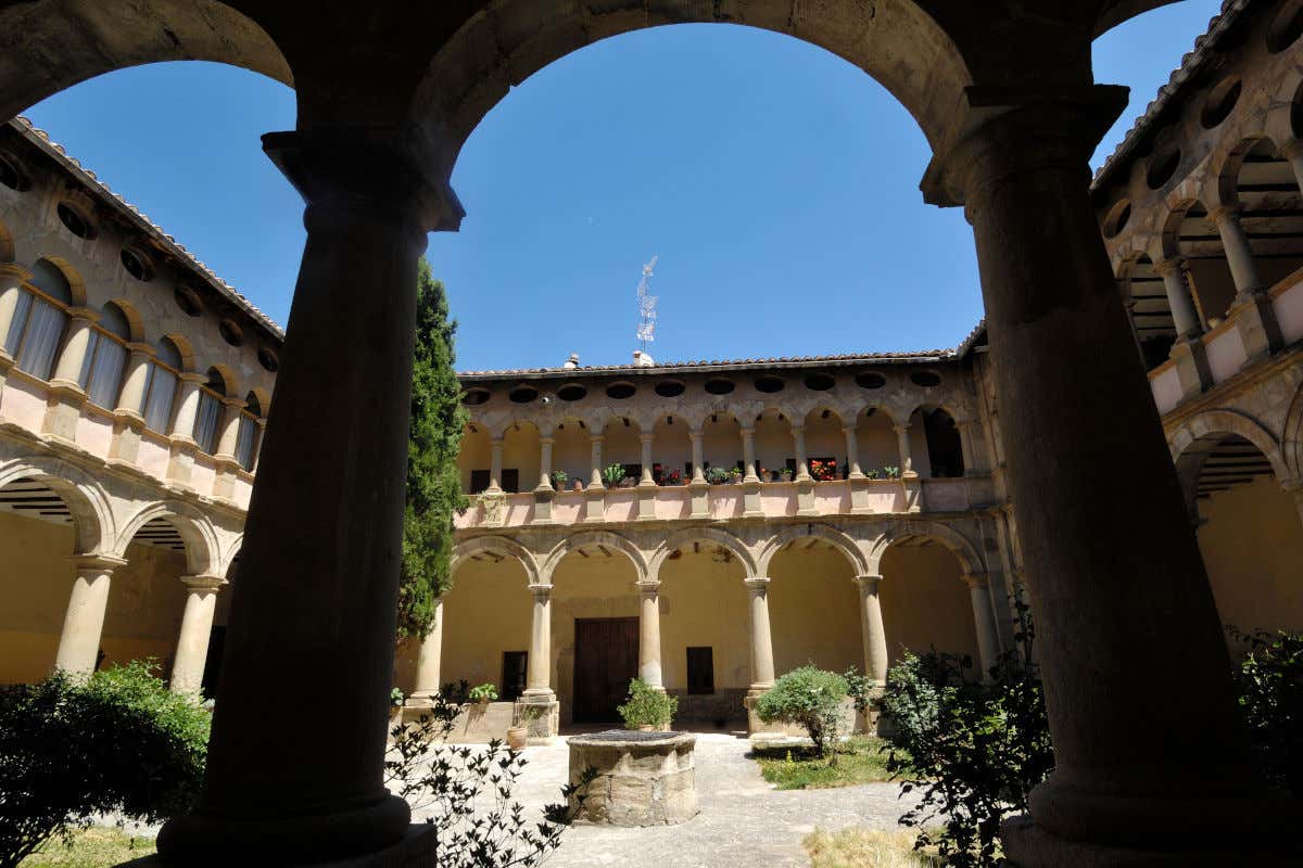 Claustro de un convento de dos pisos repleto de arcos y decorado con algunas plantas