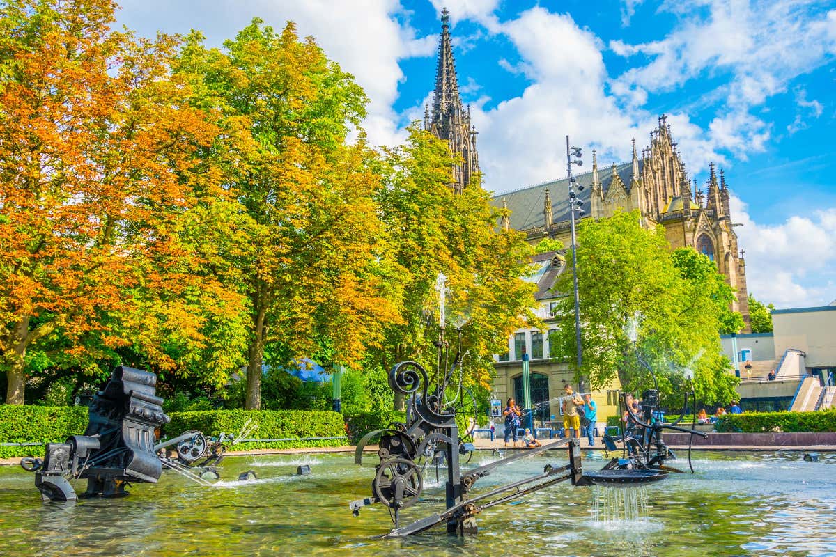 Esculturas de arte contemporáneo situadas en una fuente, con una catedral gótica de fondo