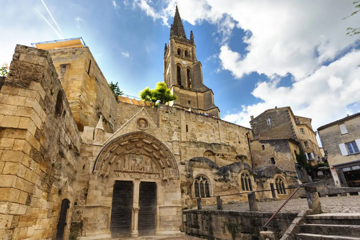 An old medieval church in Saint-Emilion a town just outside of Bordeaux, a bell tower rising high into the bright blue sky