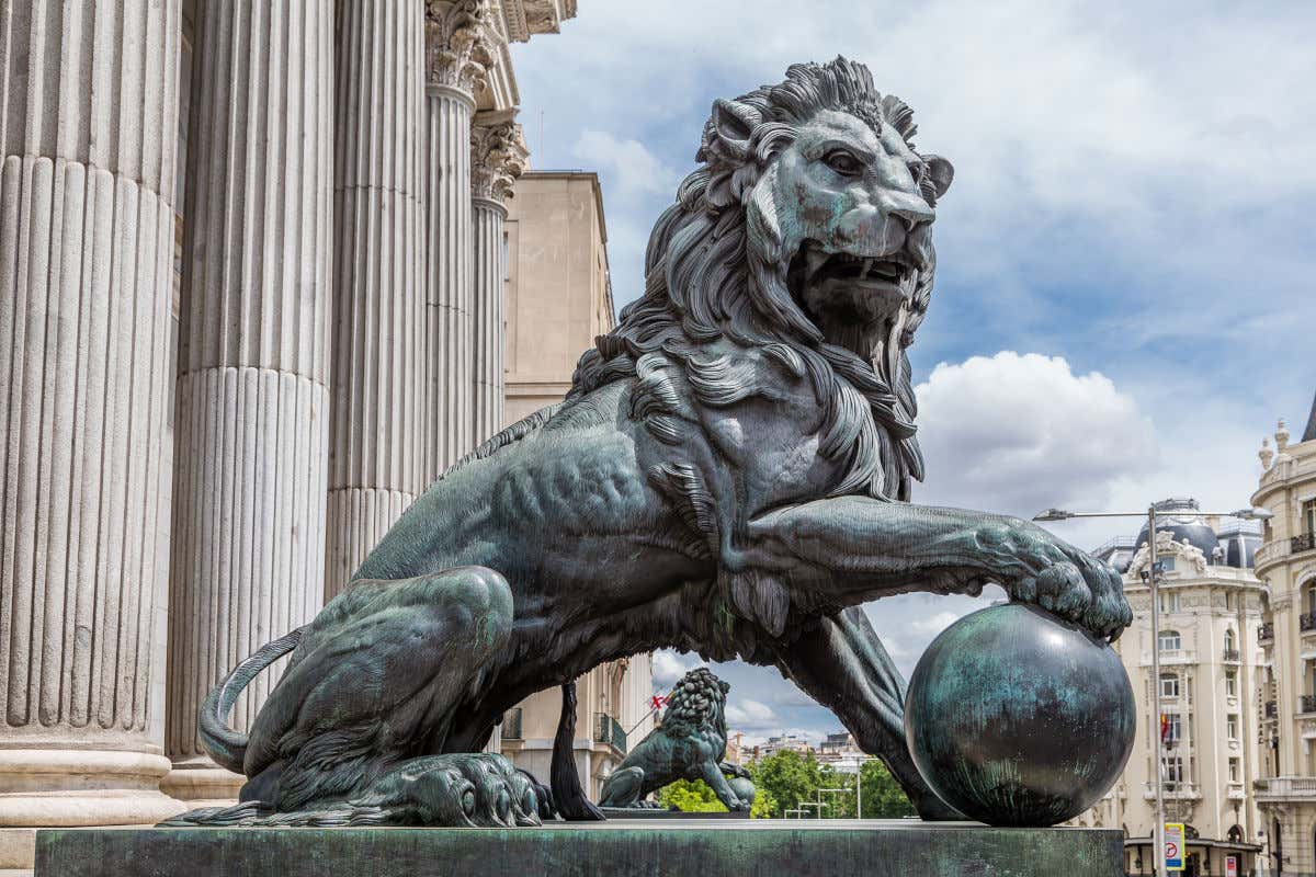 Esculturas de bronce de dos leones frente a las enormes columnas corintias del Congreso de los Diputados, en Madrid