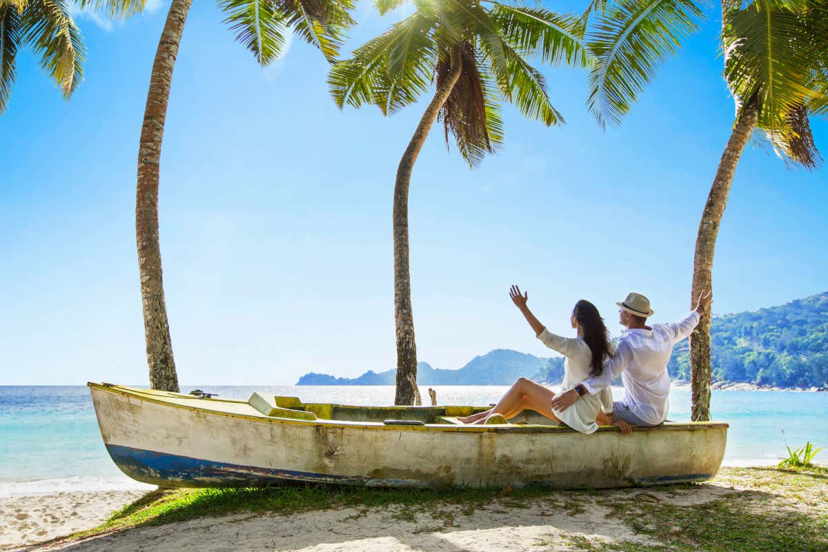 Una coppia in barca su una spiaggia sabbiosa accanto a diverse palme