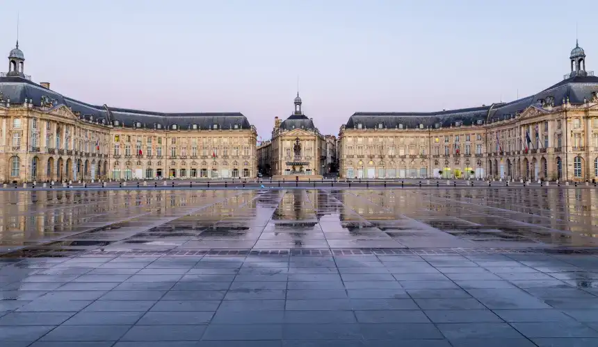 Panoramic view of Place de la Bourse, completely empty of passersby after having just rained, the water reflecting the building facade