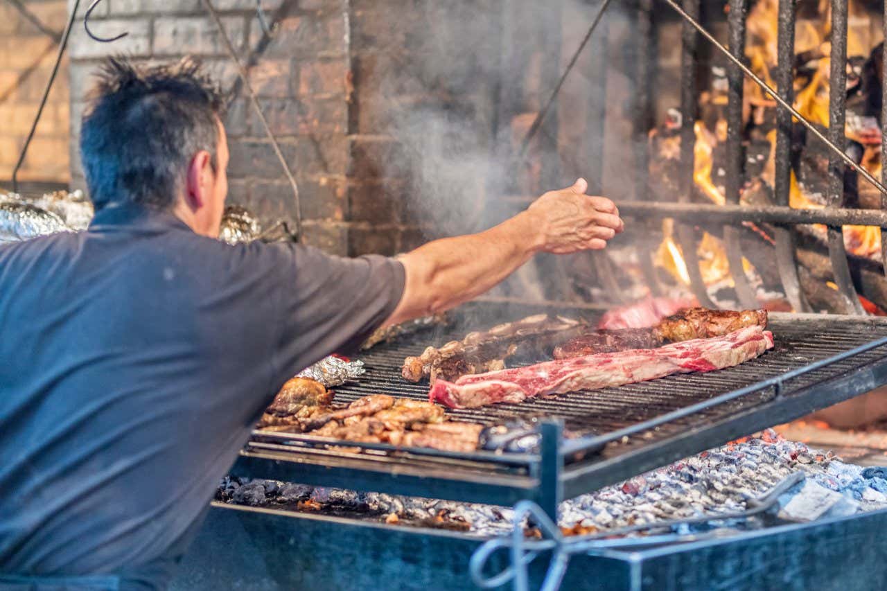 Un homme faisant cuire de la viande sur une parrilla dans le marché du port de Montevideo