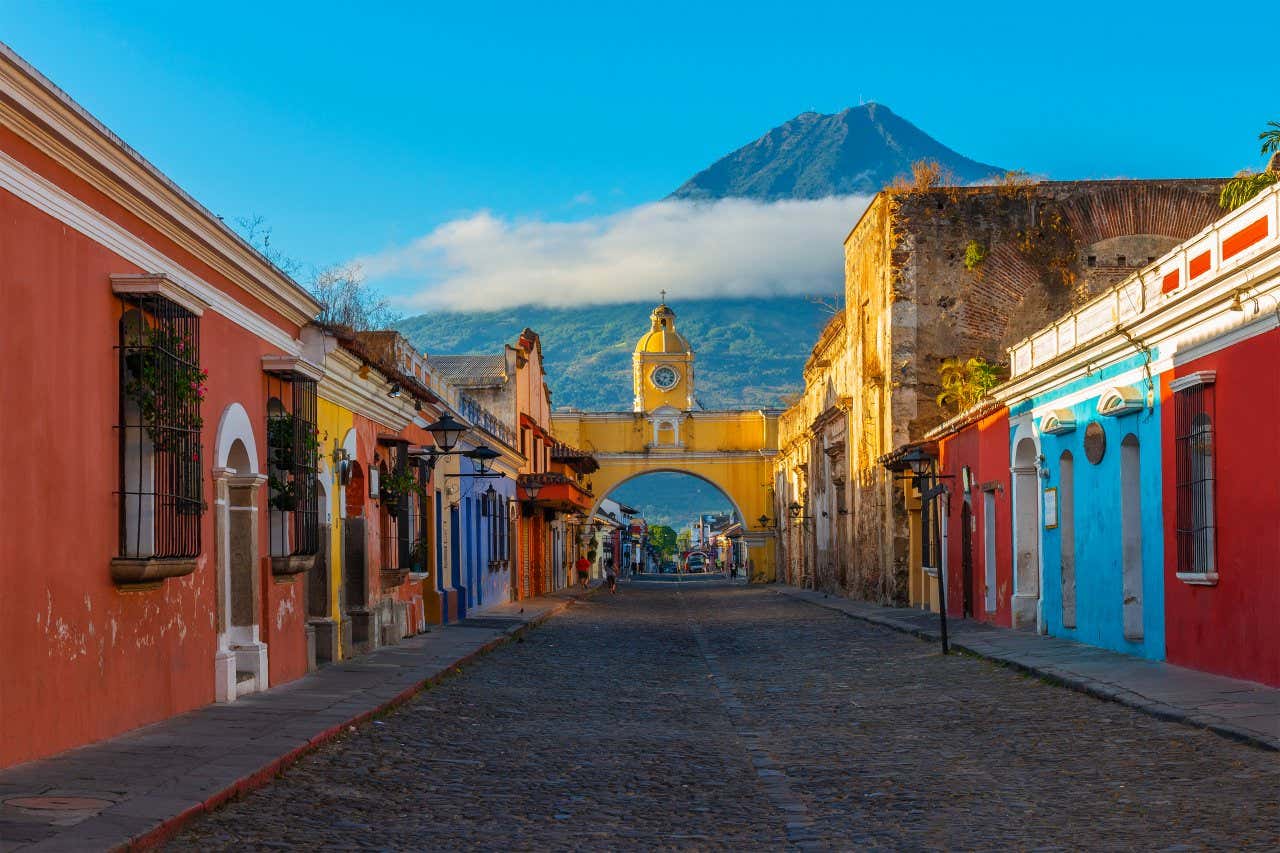 Street in the colonial town of Antigua Guatemala, with colorful buildings and the Agua volcano in the background.