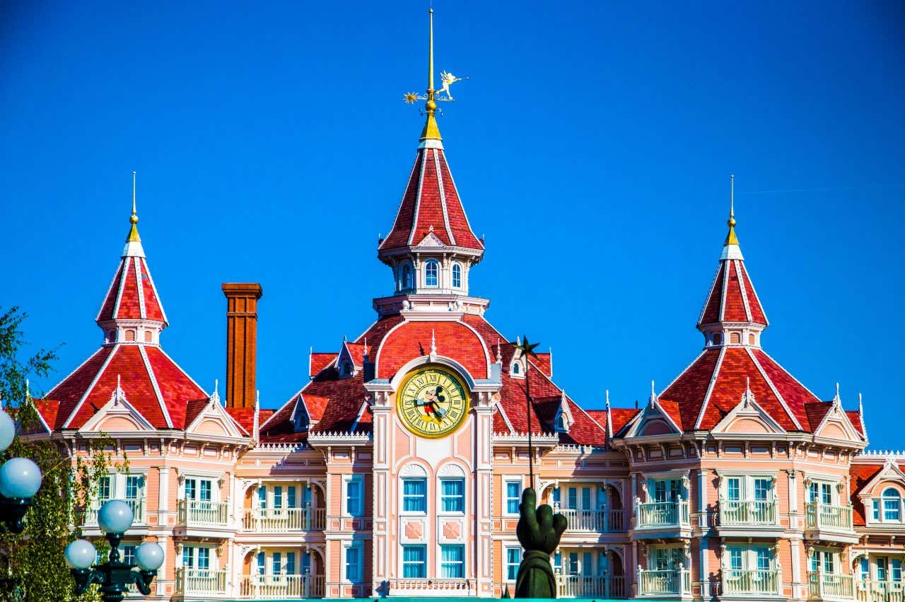 Fachada em rosa claro do Disneyland Hotel com os telhados vermelhos e um relógio com o Mickey ao centro