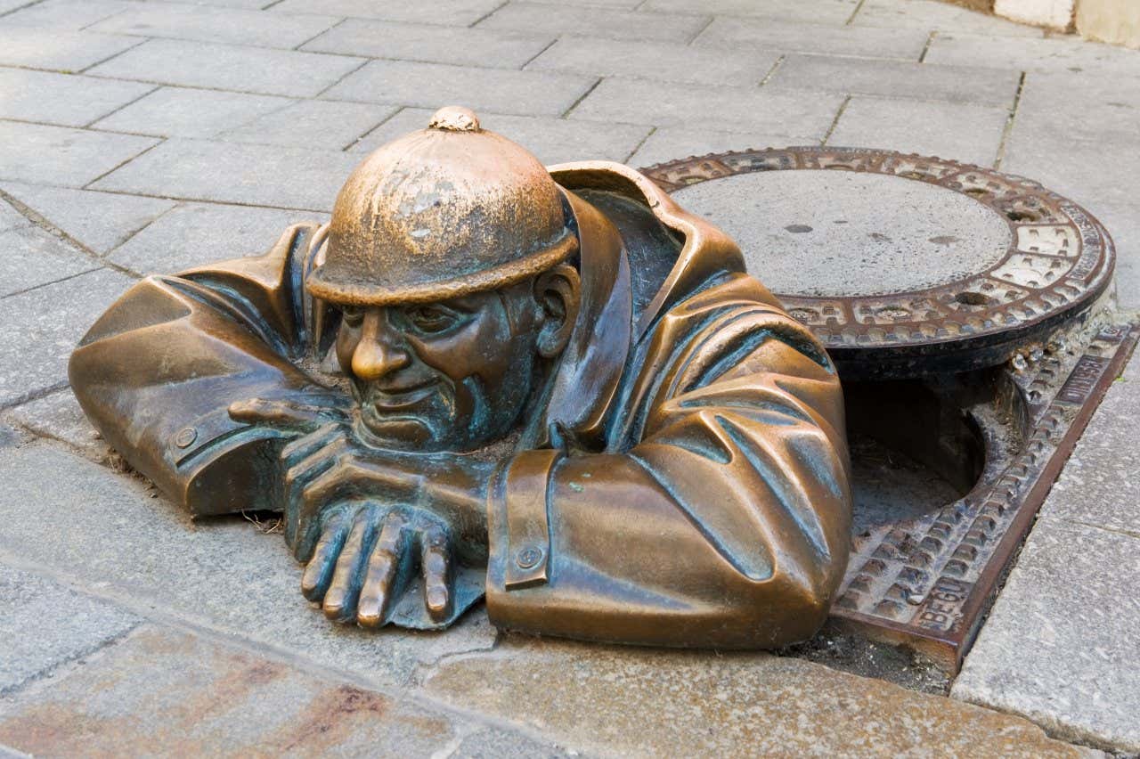 Čumil, una delle statue in bronzo di Bratislava, raffigurante un uomo sorridente con l'elmetto che fuoriesce da un tombino