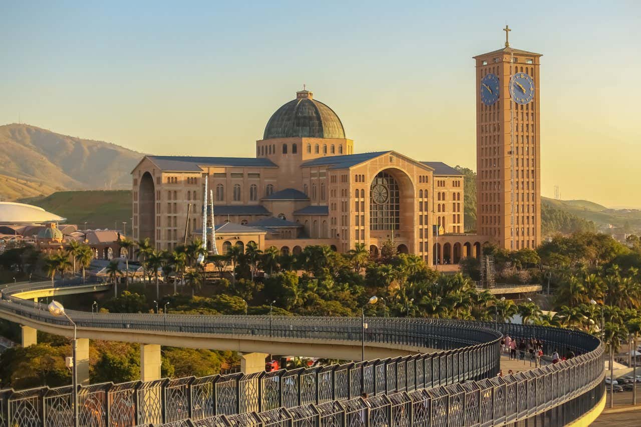 Panorâmica da basílica de Nossa Senhora aparecida com seu grande torre e a Passarela da Fé a frente com turistas caminhando