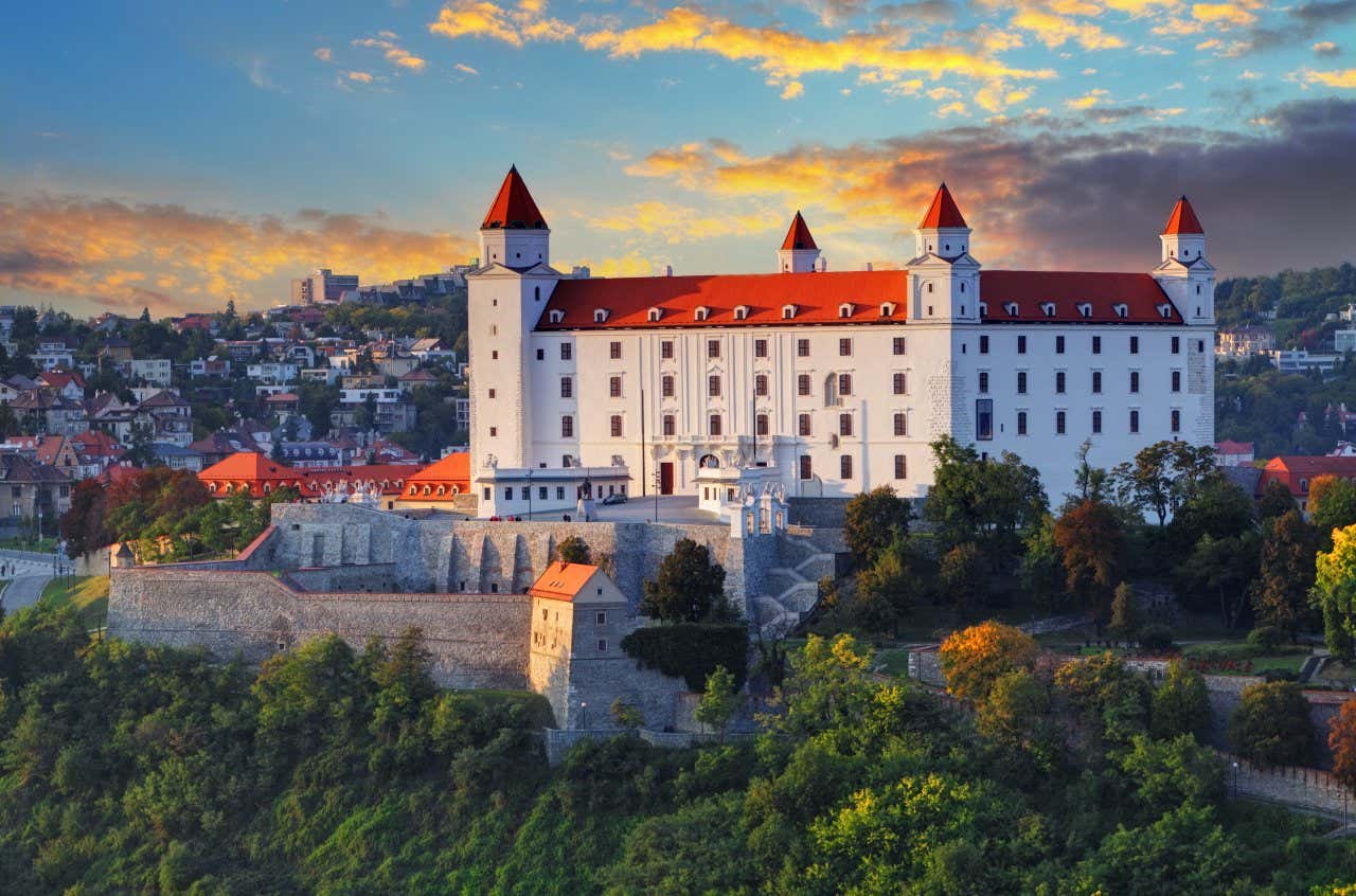 Castello di Bratislava circondato da alberi, mura ed edifici al tramonto