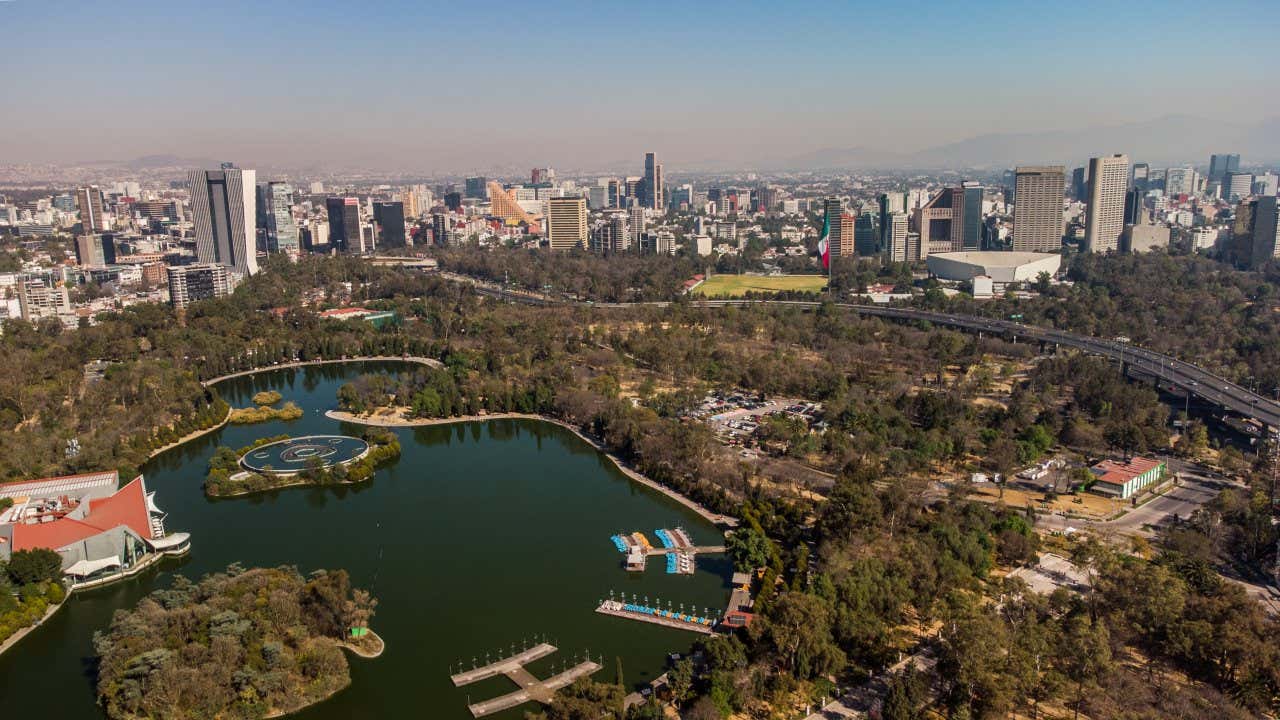 An aerial view of Chapultepec park with Mexico City seen across it.