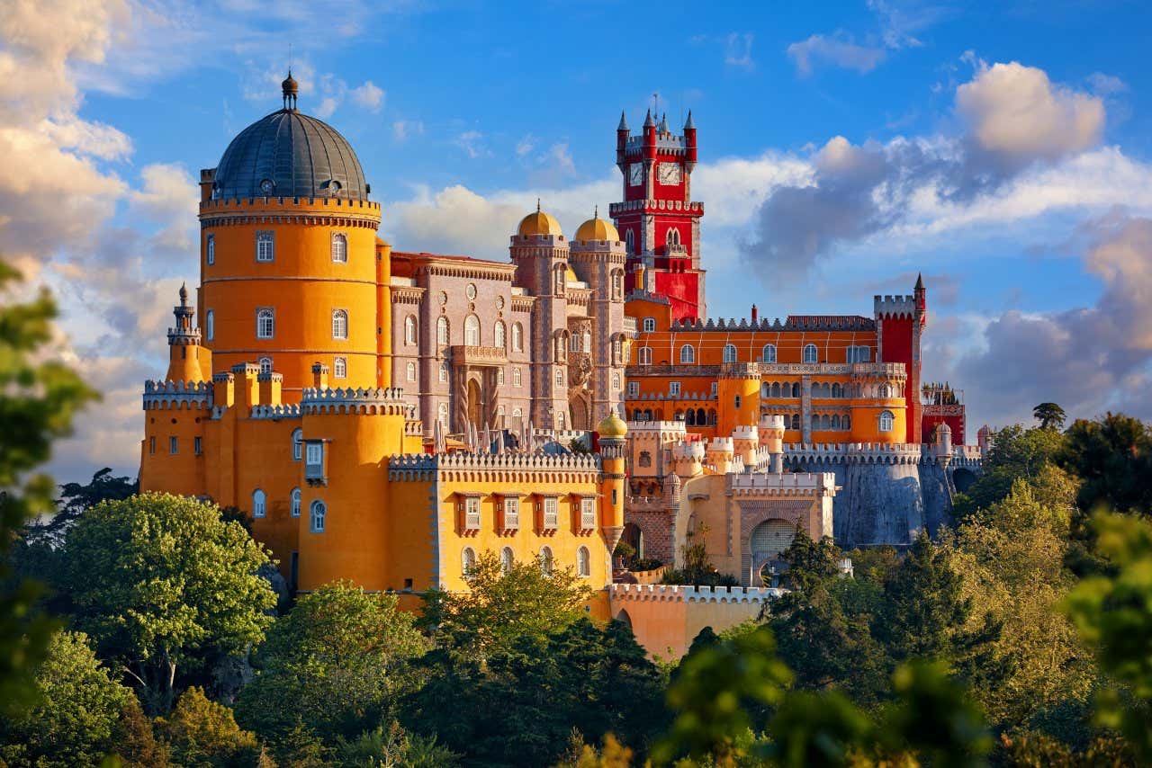 The Pena National Palace, with its distinctive red, yellow and orange exterior, against a bright blue sky