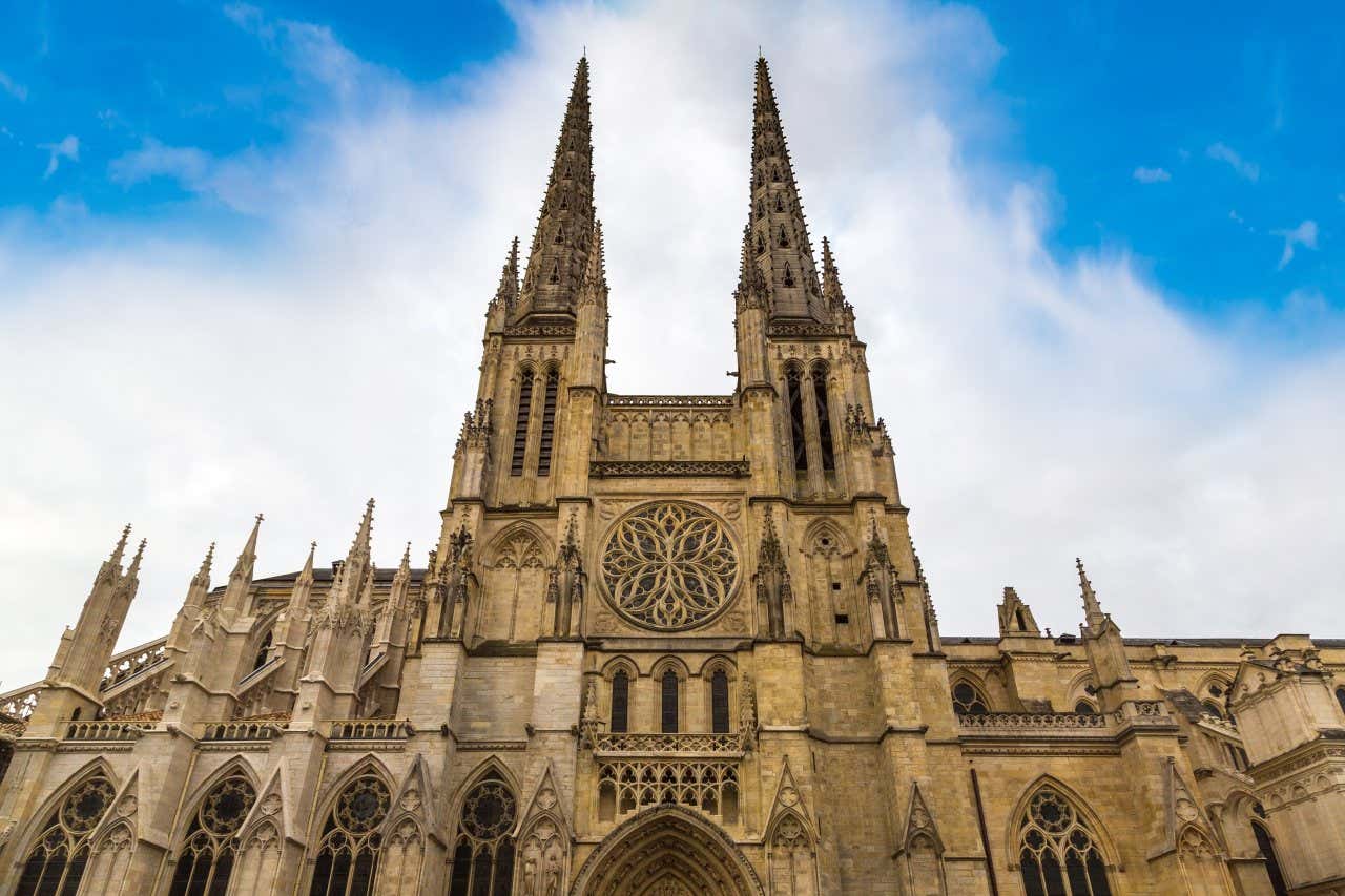 Front facing facade of St. Andrew's Catehdral, one of the top things to do in Bordeaux, against a vibrant blue sky on a sunny day