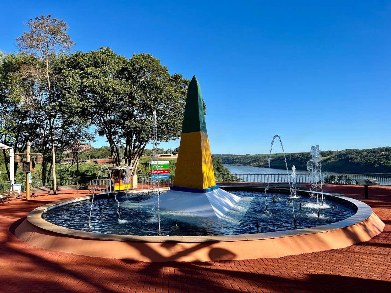 Le monument brésilien des Trois Frontières peint en vert et jaune au centre d'une fontaine