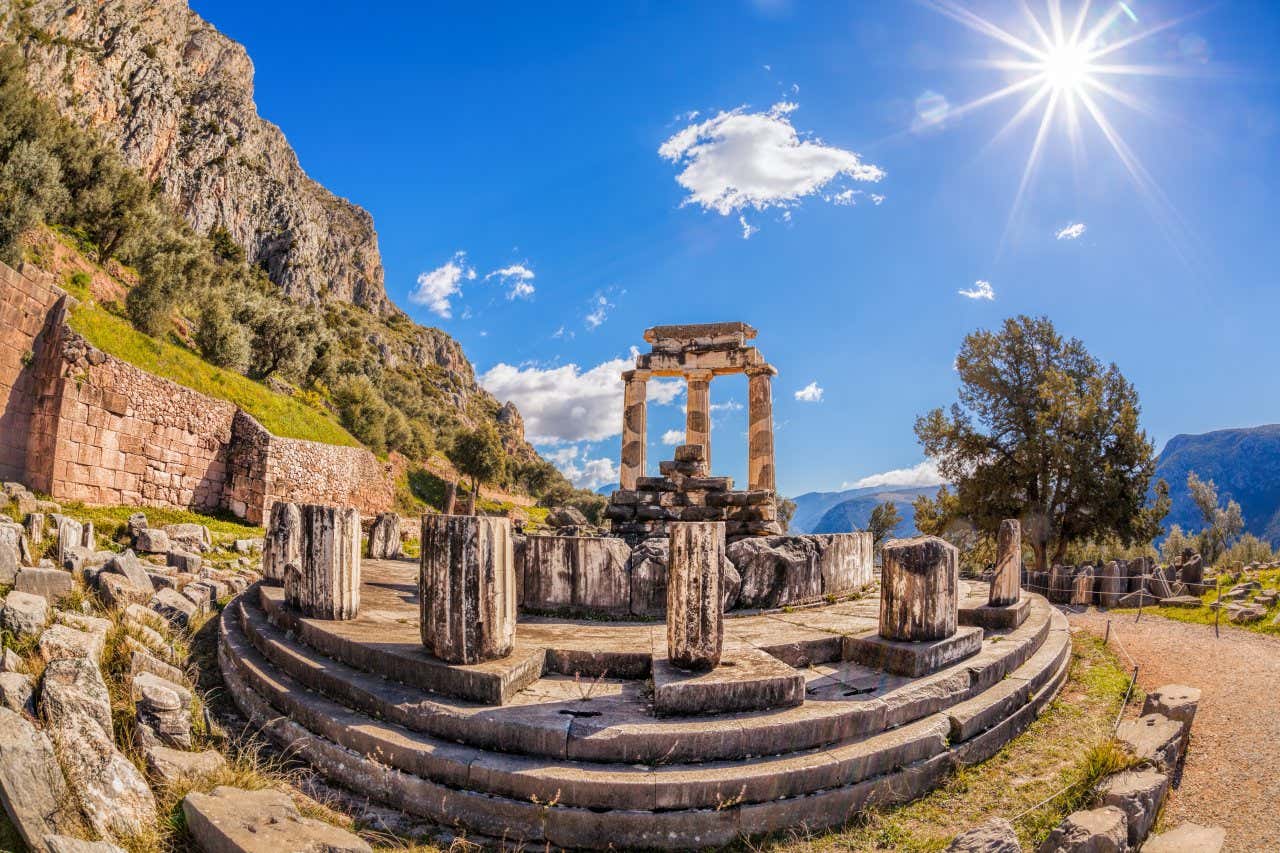 Photo en grand angle des vestiges du Temple d'Apollon de Delphes sous un ciel bleu