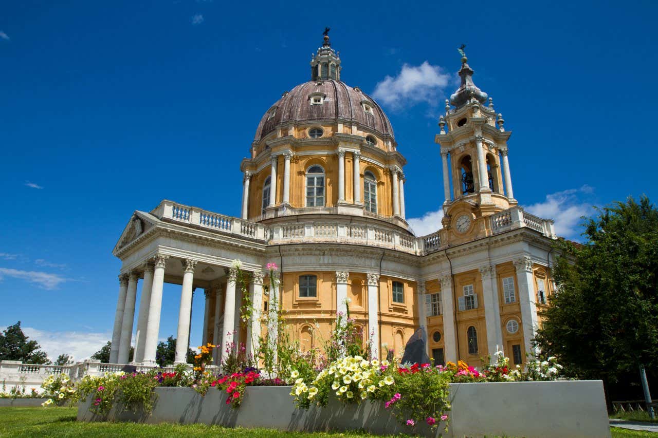 Basilique à la façade jaune entourée d'un jardin fleuri