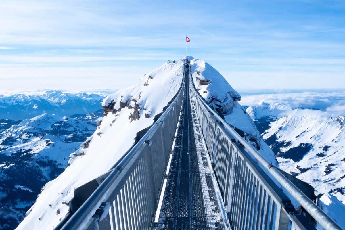 Pasarela de metal en lo alto de una montaña nevada, que sirve como mirador