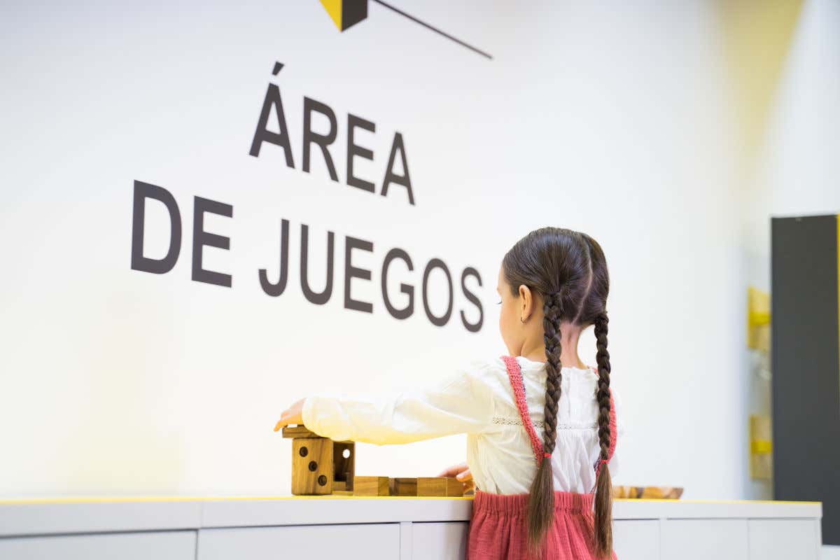 Una niña de espaldas a la cámara jugando con piezas de madera en una sala de un museo