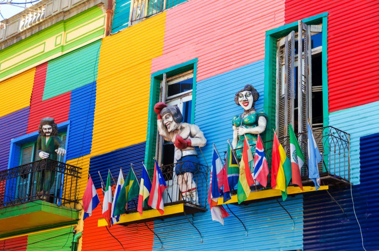 Um edifício colorido no bairro de La Boca, em Buenos Aires, com estátuas e bandeiras