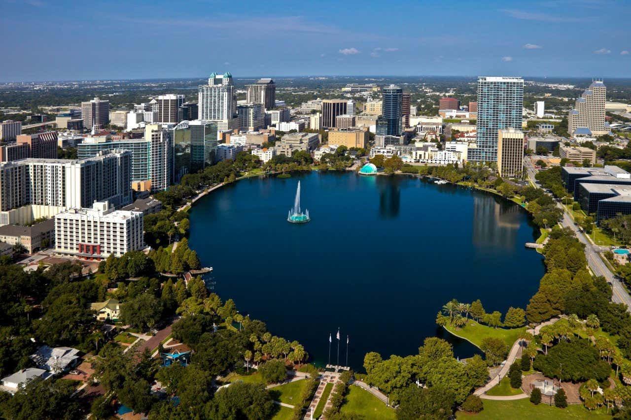 An aerial view of Lake Eola Park with the city surrounding it on a sunny day.