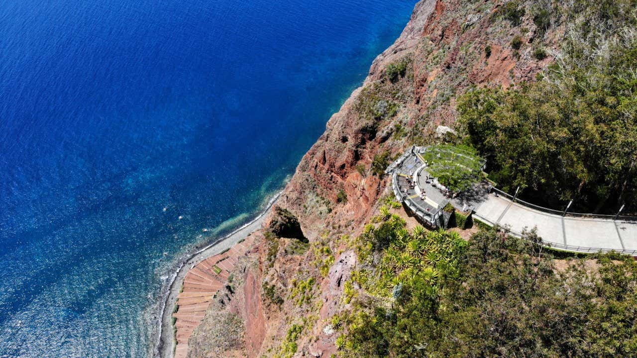 An aerial view of people standing at the Cabo Girão Viewpoint with bright blue water underneath.