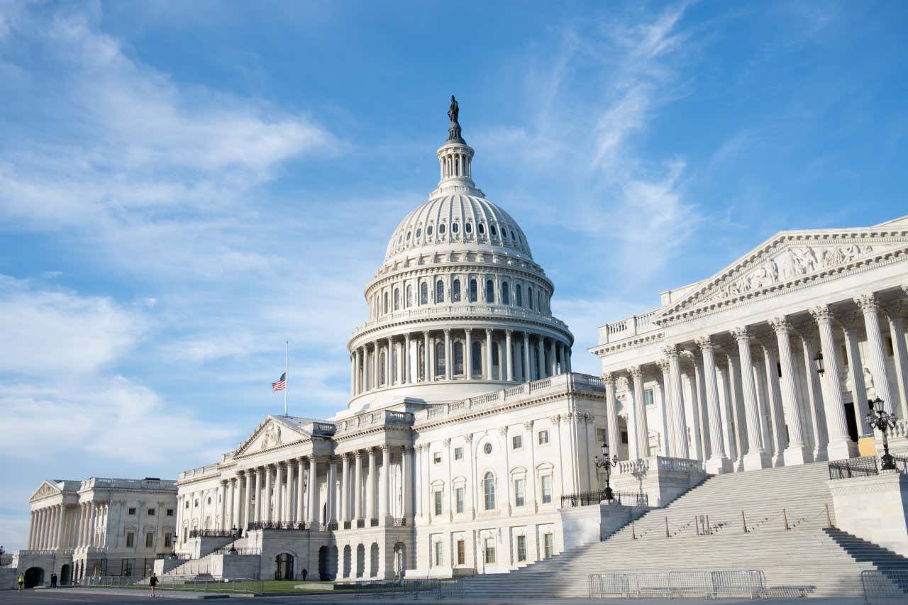 Capitol building in Washington, DC, with empty steps leading up to the columns and white building under a clear sky