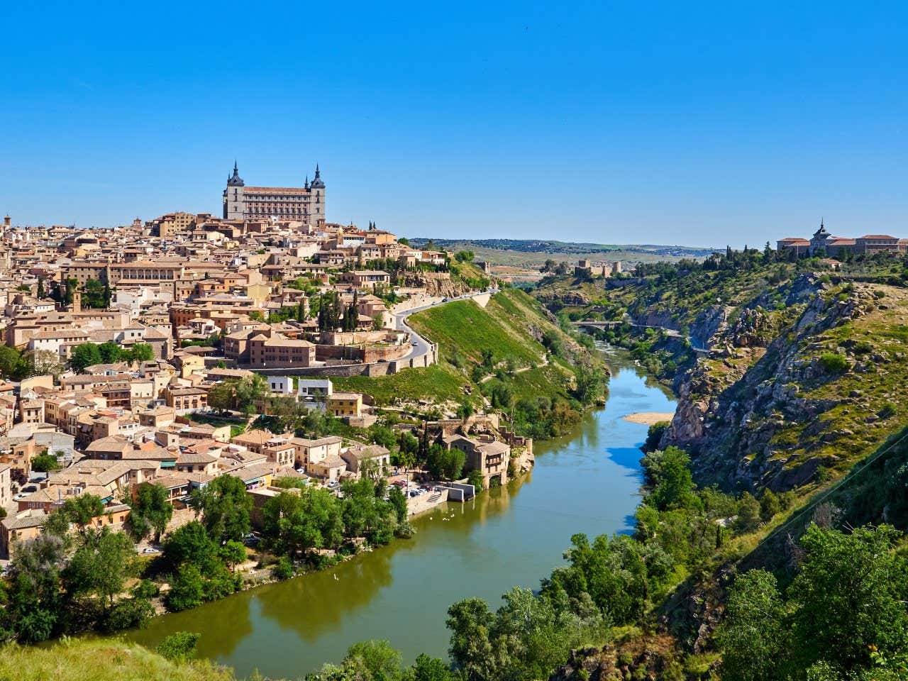 View of the old town and the Alcazar of Toledo, with the Tagus River in the foreground.