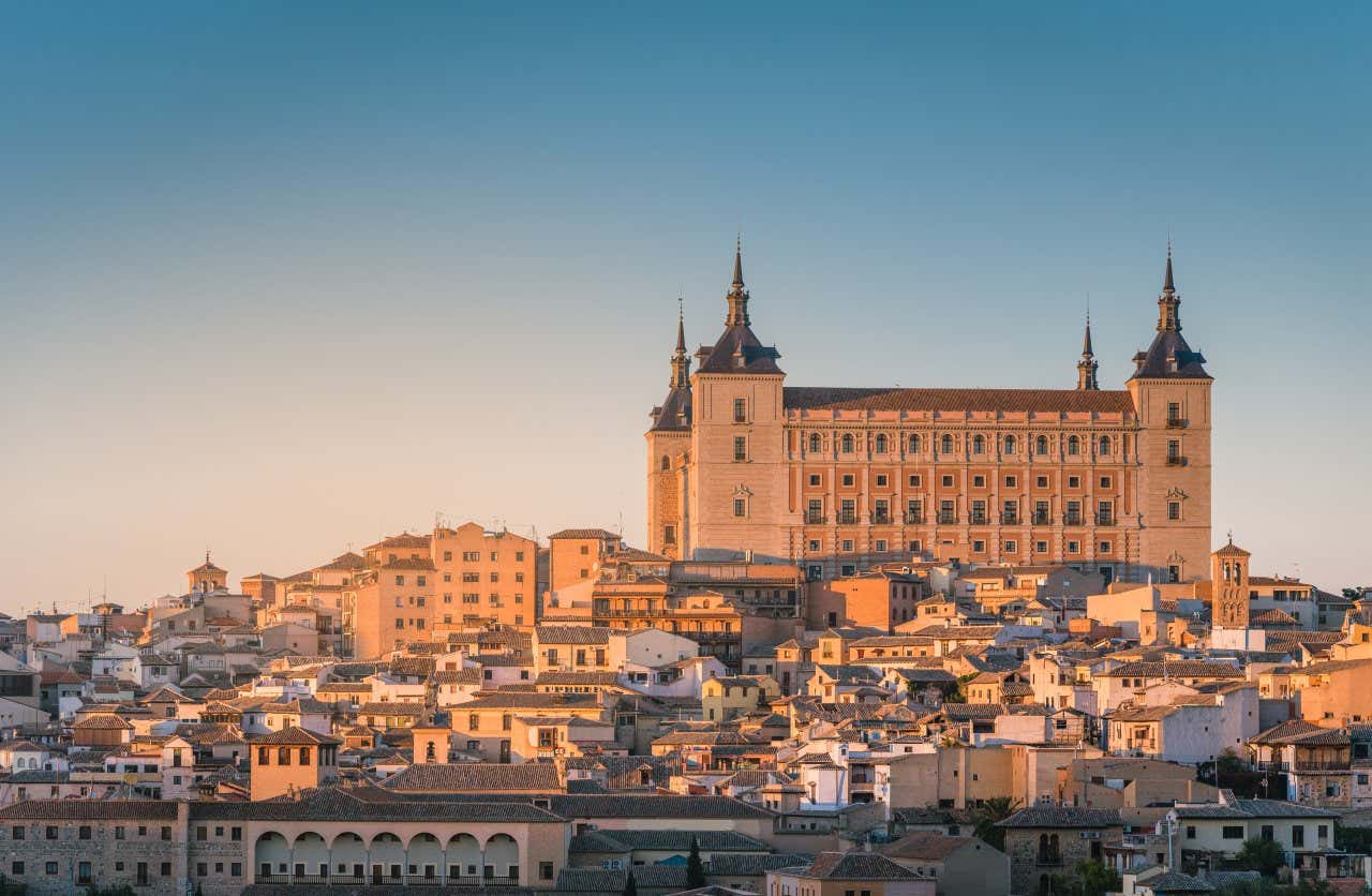 A shot of the Alcázar of Toledo as seen from afar, as the sun sets on the city.