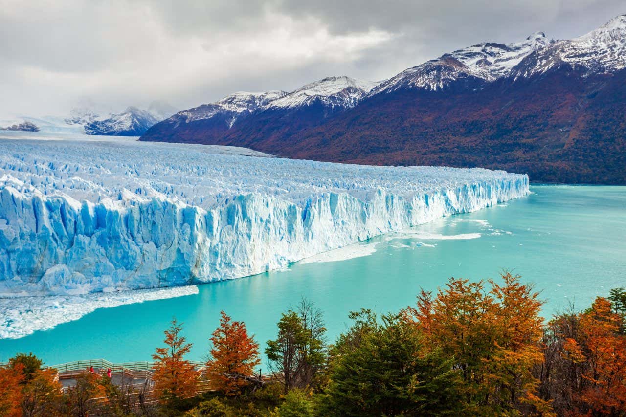 Panorâmica de um imenso bloco de gelo, o Perito Moreno, com montanhas nevadas ao fundo