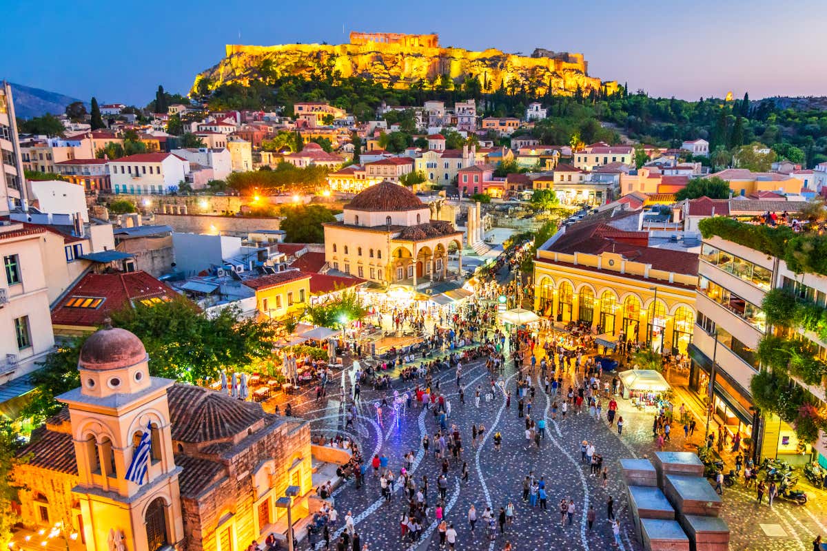 Vista aérea de la plaza Monastiraki de Atenas al caer la noche, con la colina del Acrópolis iluminada de fondo