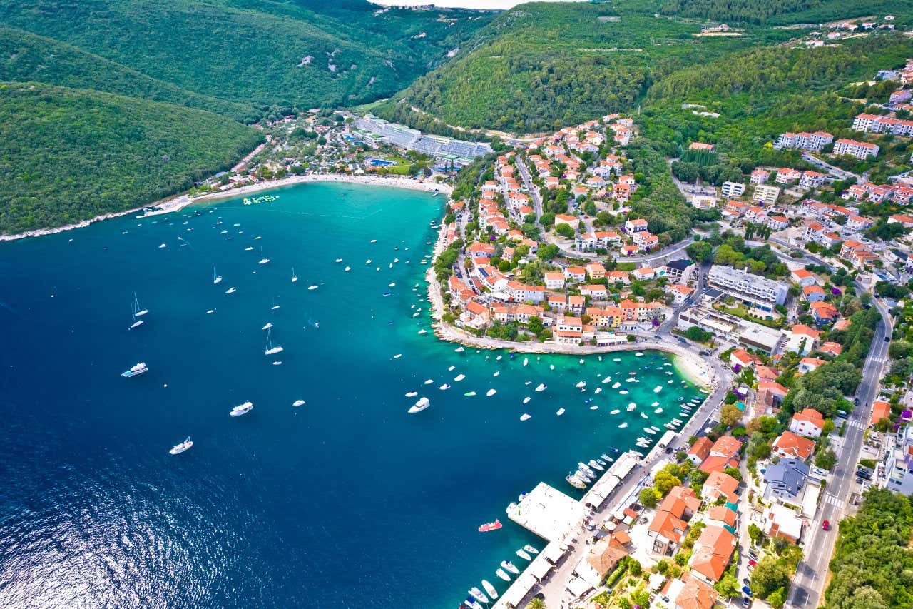 Una cittadina vista dall'alto, situata su un'insenatura sul mare e circondata da vegetazione