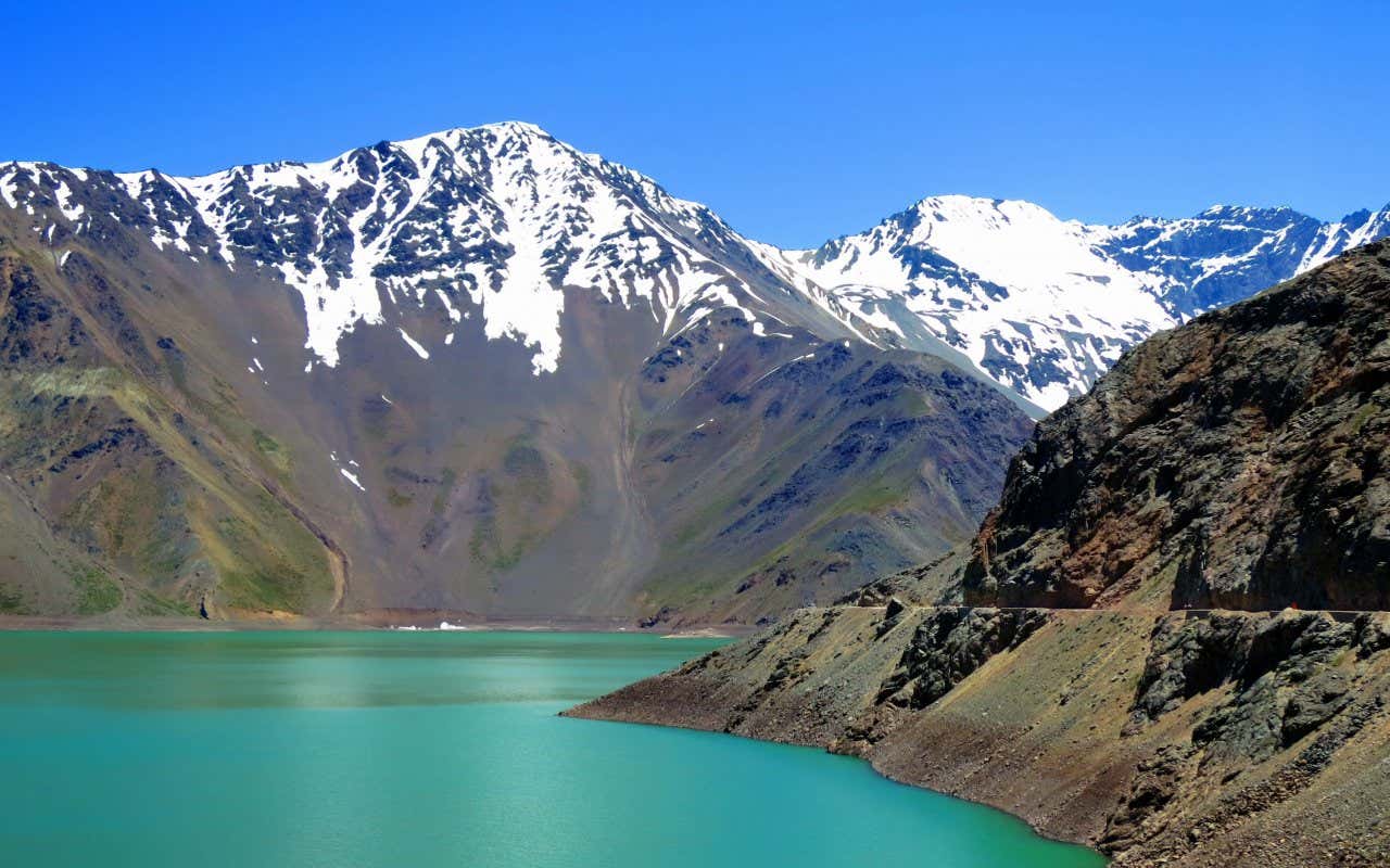 Panorâmica de um lago esverdeado rodeado de montanhas nevadas