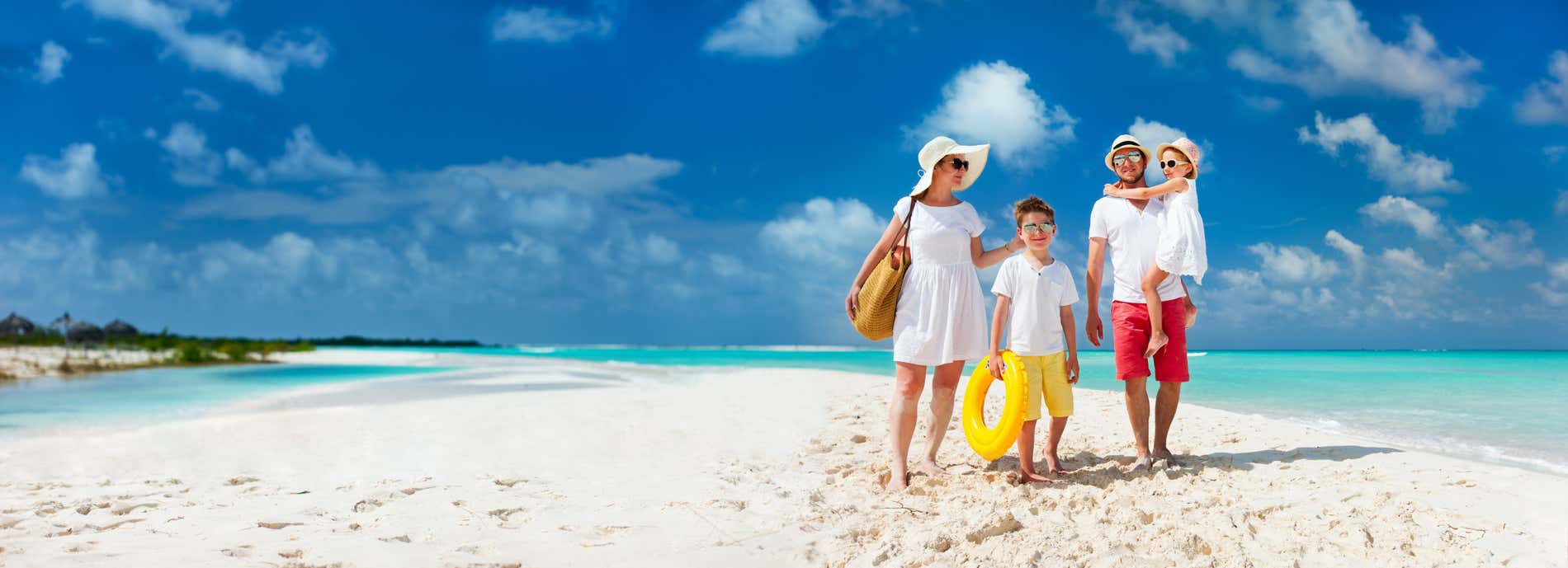 A family on a white sandy beach by turquoise water