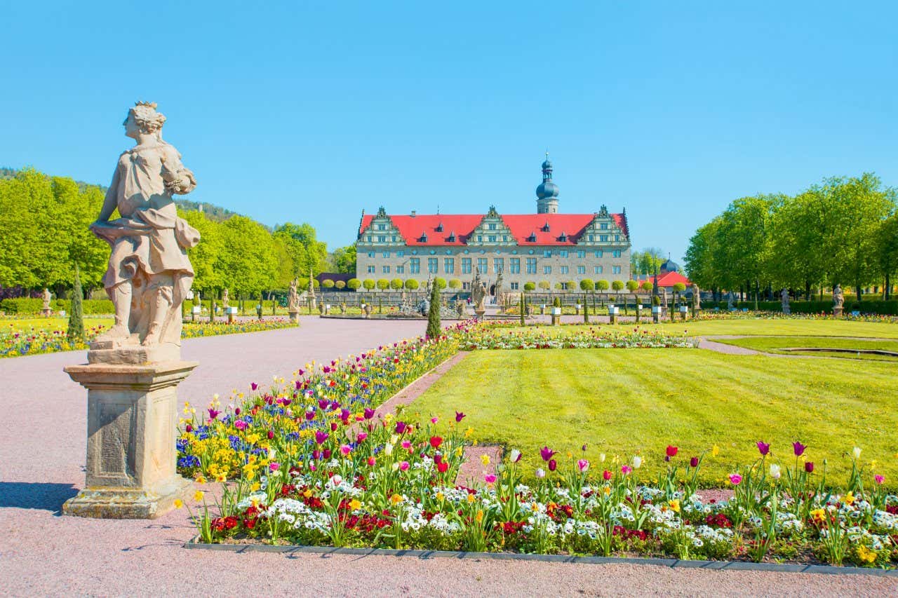 Vista do Schloss Weikersheim ao fundo de um belo jardim com uma escultura à frente