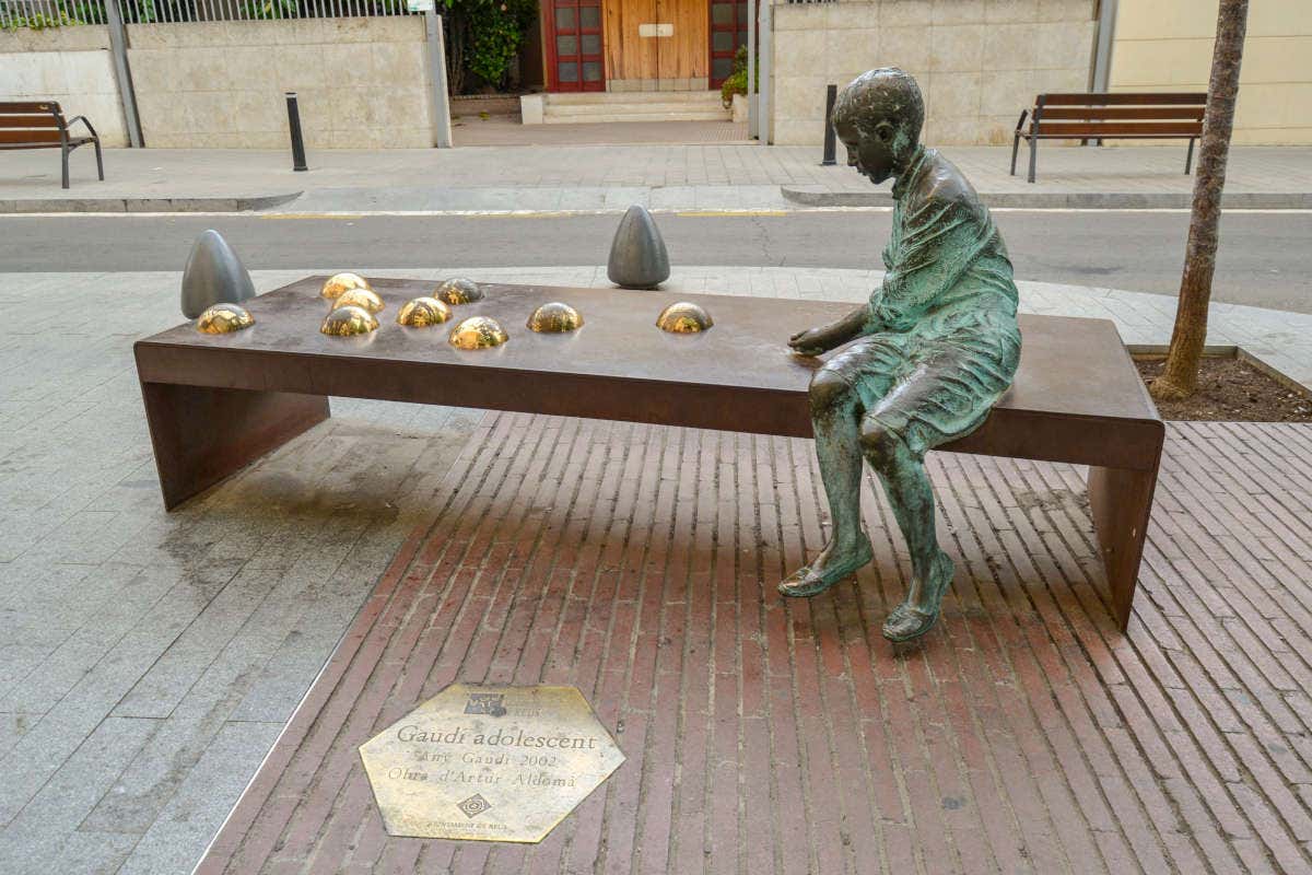 Escultura de un niño jugando en un banco de Gaudí en Reus