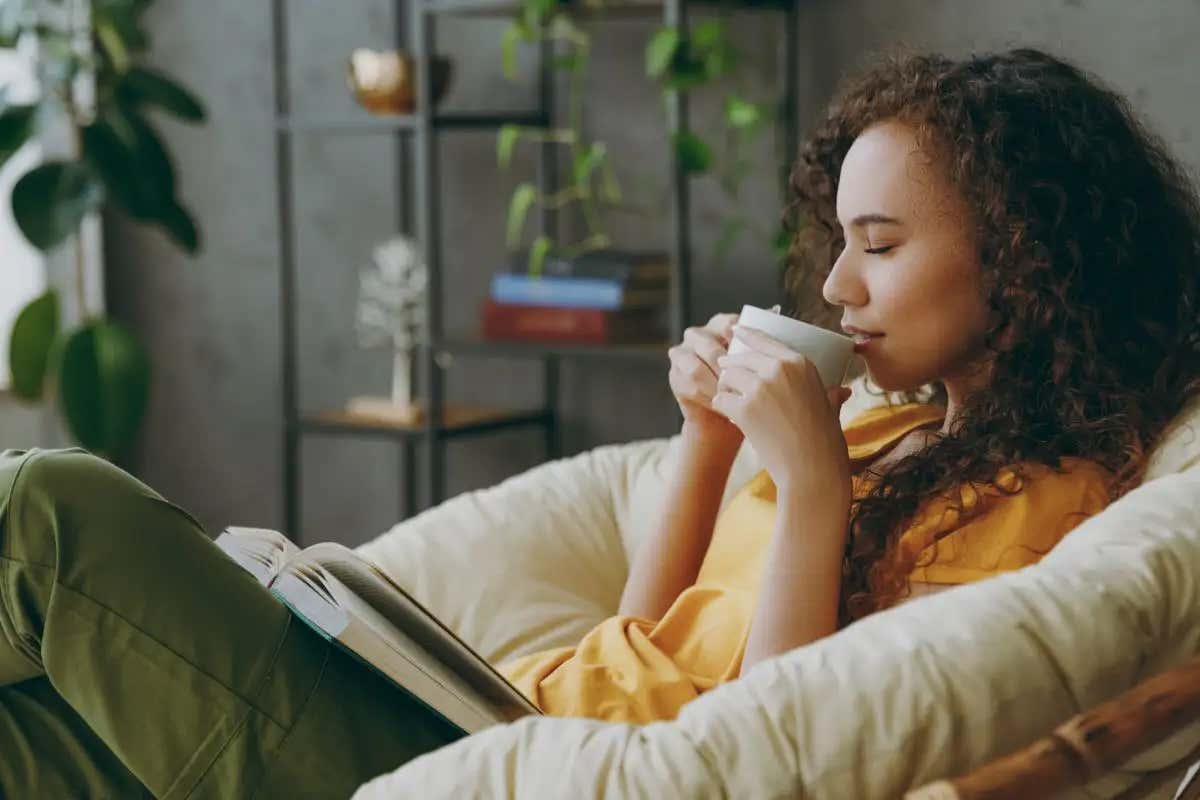 Uma mulher sentada em uma poltrona segurando uma caneca