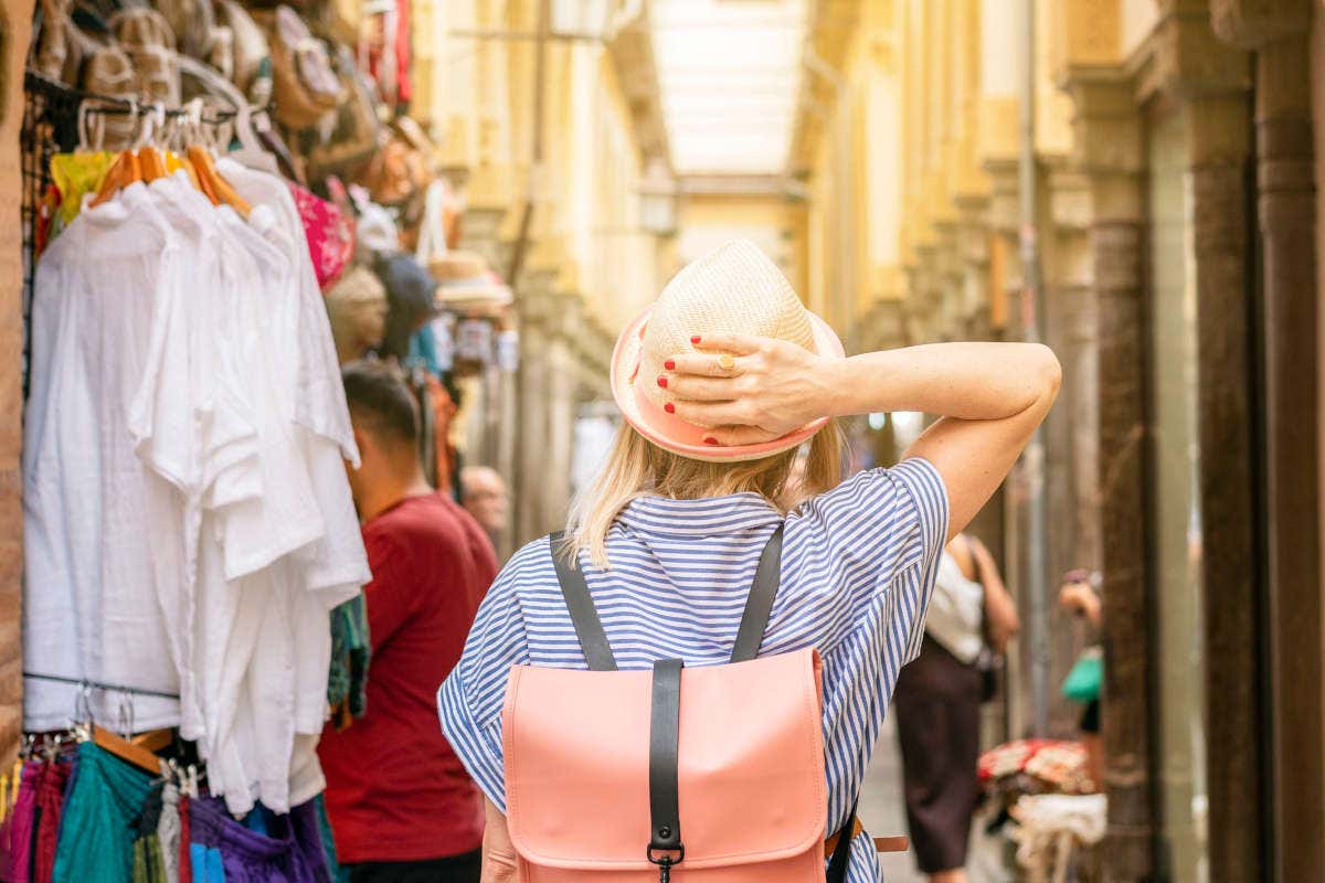 Una chica de espaldas paseando junto a las tiendas de la Alcaicería de Granada