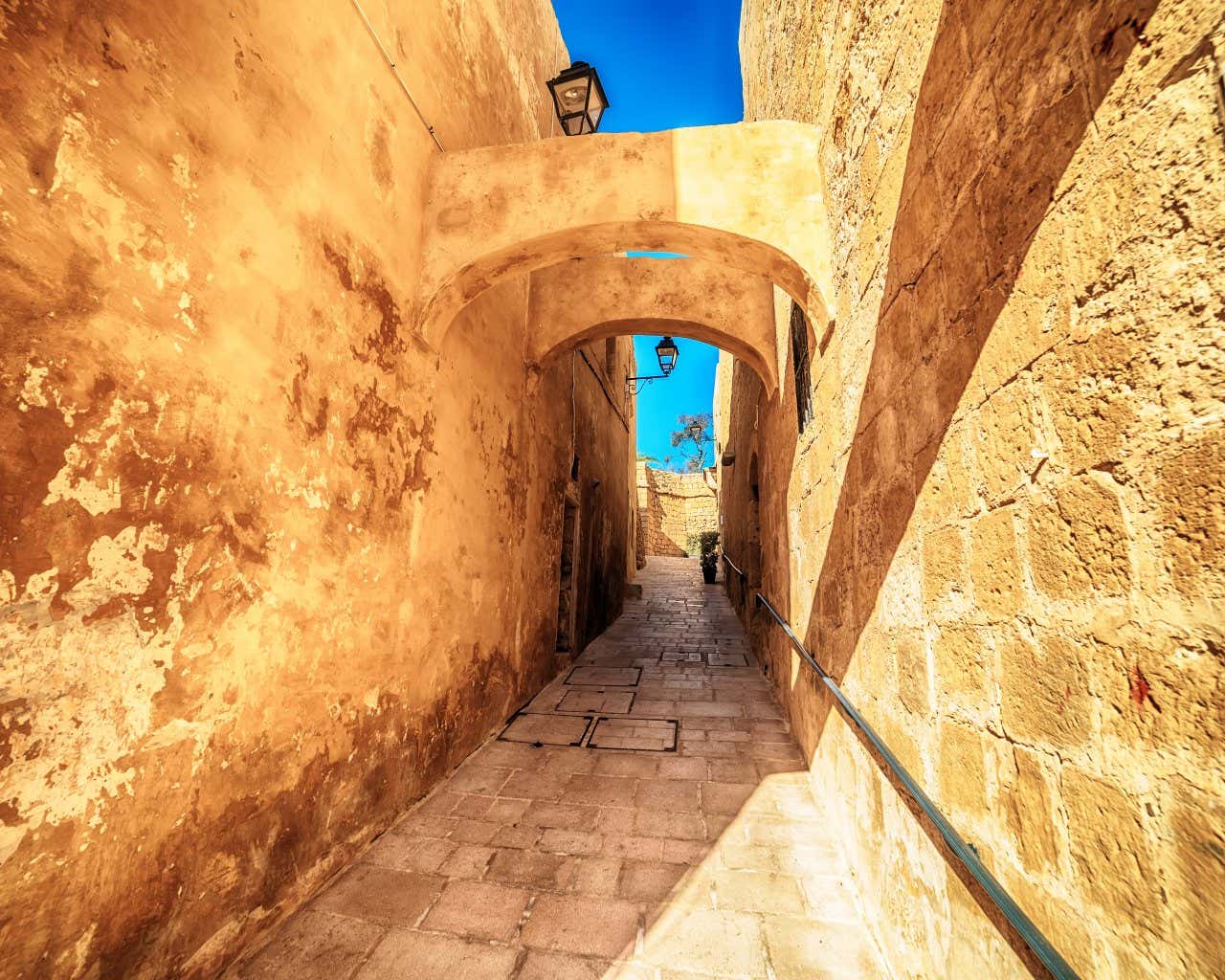 A narrow yellow stone alley on a sunny day.